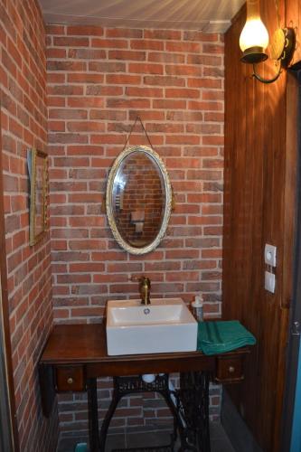 La salle de bains est pourvue d'un lavabo blanc et d'un mur en briques. dans l'établissement Amis gîte 2-4-5 pers avec jacuzzi entre Anduze et Alès, à Carnoulès