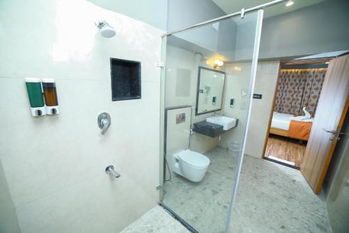 a bathroom with a shower and a toilet and a sink at Grand Palace Hotel & Spa in Yercaud