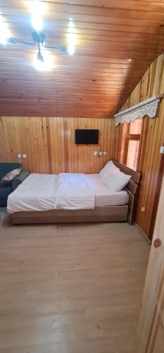 a bedroom with a large bed in a wooden room at SAHH MOTELl in Uzungol