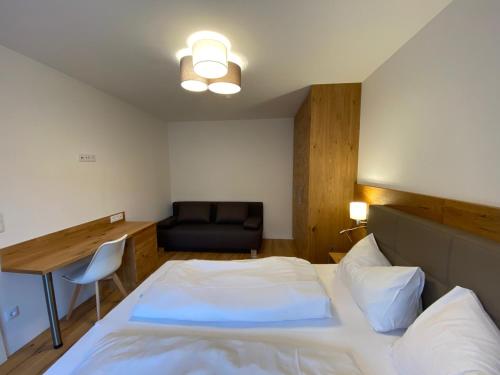 a bedroom with a bed and a desk and a chair at Apartments Freitag - H1 in Winden am See