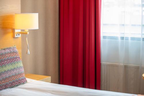 a bedroom with a red curtain and a window at Quality Hotel Ulstein in Ulsteinvik