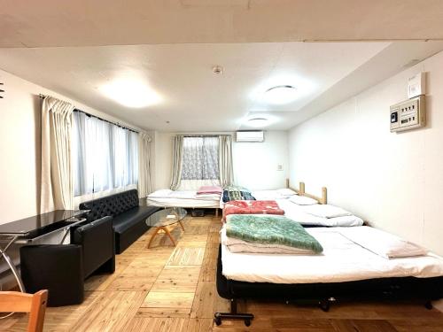 Zimmer mit 3 Betten und einem Schreibtisch. in der Unterkunft Shibasaki House 1F - Vacation STAY 13848 in Kusatsu