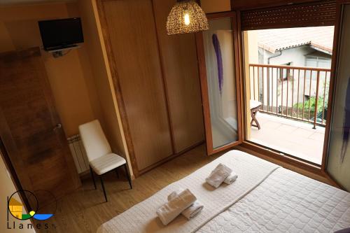 a bedroom with a bed and a window with a balcony at Adosado en LLanes in Llanes