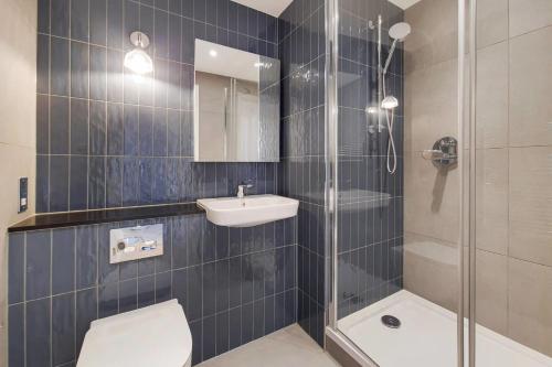 a bathroom with a shower and a toilet and a sink at Repton Gardens at Wembley Park in London