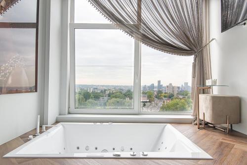a bath tub in a room with a large window at #stayhere - Unique Top Floor Loft with Hot Tub & City View in Vilnius