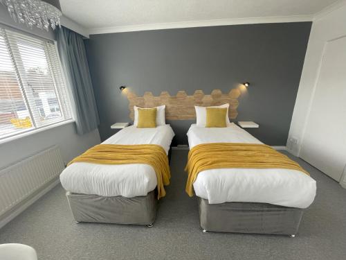 a bedroom with two beds with yellow pillows at Warwick House, 5 bedrooms, 9 beds, parking, garden in Coventry