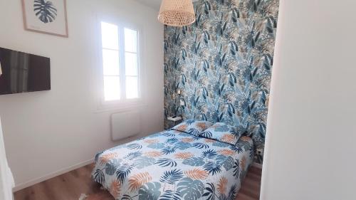 - une chambre avec un lit aux motifs bleus et blancs dans l'établissement Le Grain de Sable, à Royan