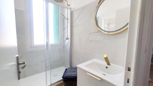 une salle de bain blanche avec un lavabo et un miroir dans l'établissement Le Grain de Sable, à Royan