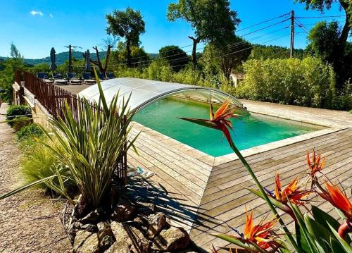 - une piscine avec une terrasse en bois et quelques fleurs dans l'établissement Logement 60 m2 au calme piscine et flipper, à Grimaud