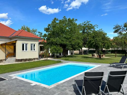 a swimming pool with chairs and a house at Tisza Love in Poroszló