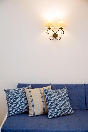 a blue couch with pillows and a light on the wall at Ca Sa Vilda in Es Pujols