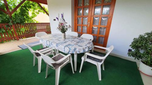 a table with white chairs and a vase of flowers at Apartment Siofok, Somogy 7 in Siófok