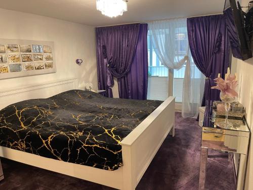菲林根－施文寧根的住宿－Luxus Domizil，一间卧室配有一张大床和紫色窗帘