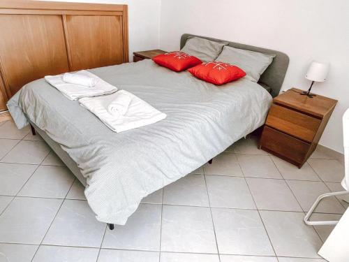 a bed with two red pillows on top of it at Seaside room in a Peniche townhouse featuring a private bathroom and shared access to the swimming pool and kitchen in Atouguia da Baleia