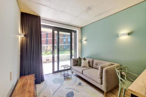 a living room with a couch and a large window at Repton Gardens at Wembley Park in London