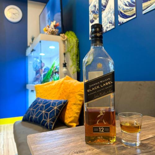 a bottle of whiskey sitting on a table next to a glass at Casas Reales Staycation & Rentals in Biñan