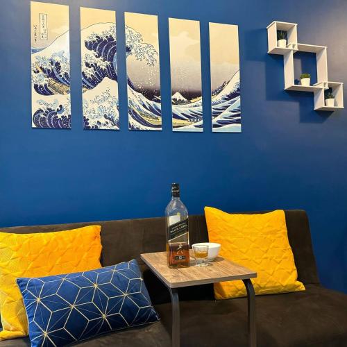 a living room with a couch and a blue wall with paintings at Casas Reales Staycation & Rentals in Biñan