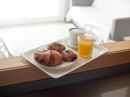 un plato con dos pastas y un vaso de zumo de naranja en Aparthotel Solifemar, en Castelldefels