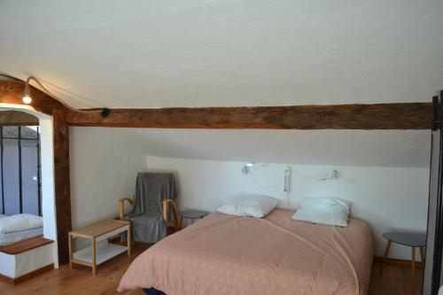 une chambre avec un lit et une chaise dans l'établissement Convivial gîte 6-10-13 pers avec jacuzzi Cévennes entre Anduze et Alès, à Carnoulès