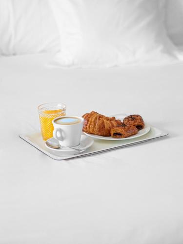 bandeja con un plato de bollería y una taza de café en Aparthotel Solifemar, en Castelldefels