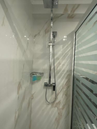 La salle de bains est pourvue d'une douche dans un mur blanc. dans l'établissement Selefkos Palace, à Igoumenítsa