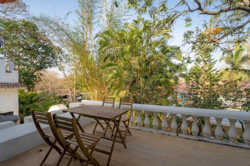 a wooden table and chairs on a balcony with trees at LohonoStays Villa Santorini in Alibag