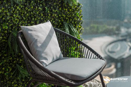 a wicker chair with a pillow in front of a bush at Fashion avenue Dubai Mall -The Residence in Dubai