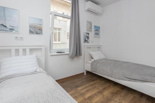 a white bedroom with two beds and a window at The Central House 1 in Burgas City