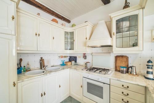 a kitchen with white cabinets and a stove and sink at Perfume House in Marciana