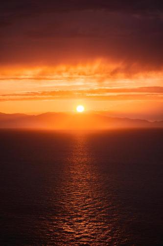 a sunset over the ocean with the sun in the sky at Perfume House in Marciana