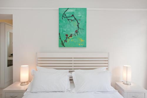 a bedroom with a bed with white pillows and a painting at The Queen Of Calitzdorp in Calitzdorp