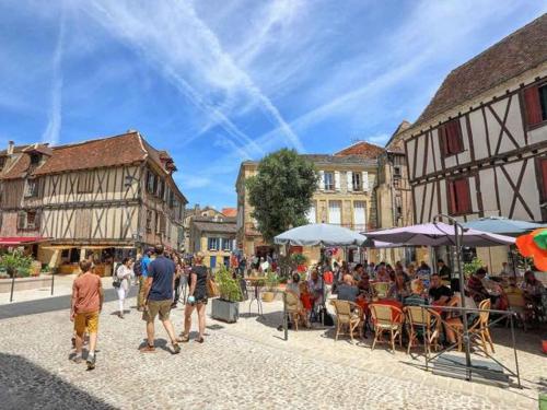 a group of people sitting at tables in a street at Maison charmante avec jardin in Coutras