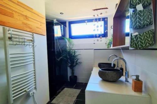 La salle de bains est pourvue d'un lavabo et d'un comptoir avec une fenêtre. dans l'établissement Les jardins du Lez * Piscine*Jardin* Proche mer, à Montpellier