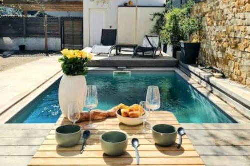 une table avec du pain et des verres à vin à côté d'une piscine dans l'établissement Les jardins du Lez * Piscine*Jardin* Proche mer, à Montpellier