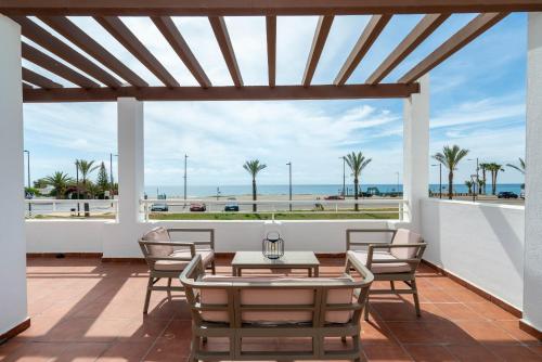 a patio with a table and chairs and a view of the ocean at AlmeriaSuite Mojacar Breeze Apartments in Mojácar