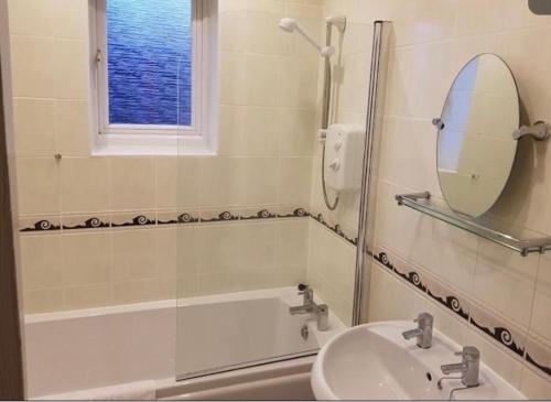 e bagno con lavandino, specchio e vasca. di Pinfold Court Apartments a Knowsley