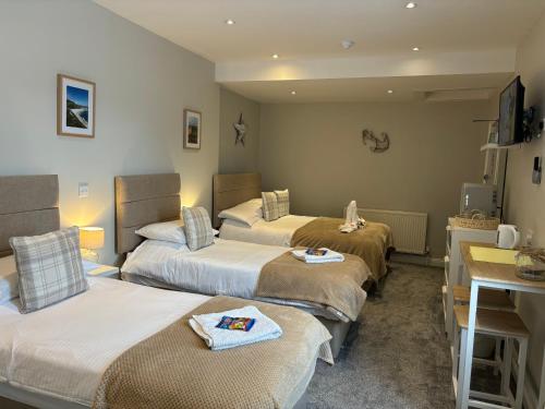 una camera d'albergo con tre letti e un lavandino di Calm sea guesthouse a Weymouth