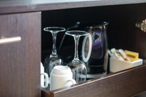 a cabinet with two wine glasses and a coffee mug at Quality Hotel Ulstein in Ulsteinvik