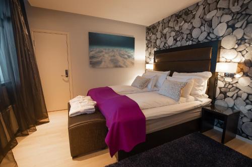 a bedroom with a large bed with a purple blanket on it at Quality Hotel Ulstein in Ulsteinvik