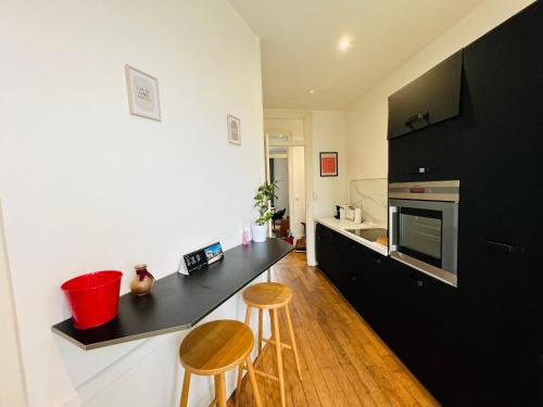 une cuisine avec un comptoir noir et deux tabourets dans l'établissement Le Poincaré! - Appartement T3, à Nancy
