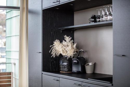 a black cabinet with a vase with flowers in it at Quality Hotel Ulstein in Ulsteinvik