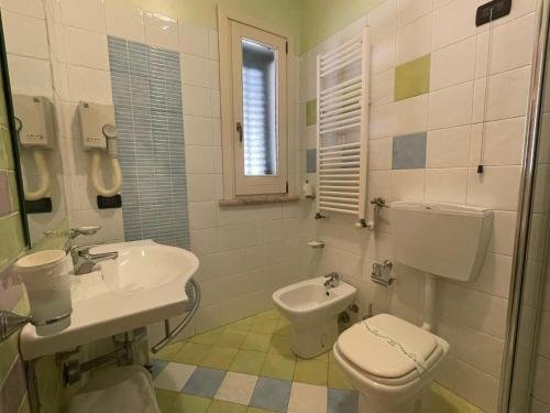 a white bathroom with a toilet and a sink at Cerri Hotel in Castellammare del Golfo