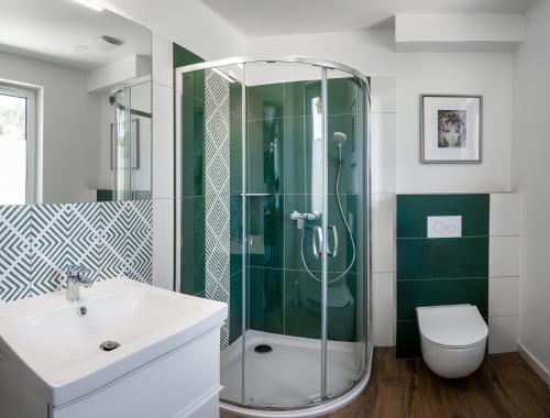 a bathroom with a shower and a sink and a toilet at Apartamenty Wczasowa - z widokiem na góry, parkingiem, rowerownią in Kudowa-Zdrój