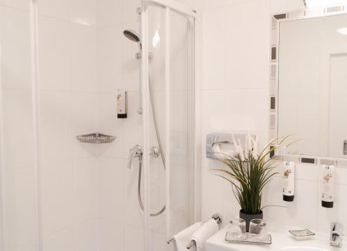 baño blanco con ducha y lavamanos en KRACHER Guesthouse No 5, en Illmitz