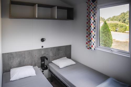 聖于連－德朗德的住宿－Camping Village de la Guyonnière，带窗户的客房内的两张床