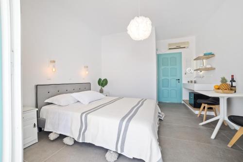 a white bedroom with a bed and a desk at Naxos Cave Suites in Stelida