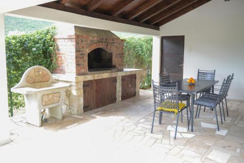 un patio con horno de ladrillo, mesa y sillas en Holiday Home Vemini en Mostar