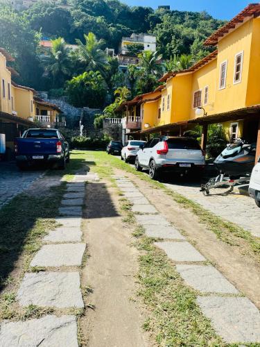 a cobblestone street with parked cars and buildings at Casa na praia in Arraial do Cabo