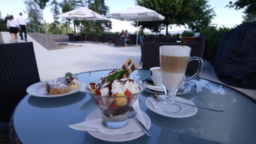 a table with a cup of coffee and a bowl of desserts at Lázeňský hotel Pyramida in Františkovy Lázně