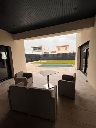 un salon avec une table et des chaises et une piscine dans l'établissement Villa à Cébazat, à Cébazat